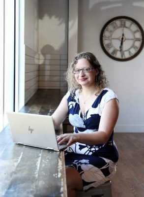 Founder Laura Barr sitting at a table with her computer.